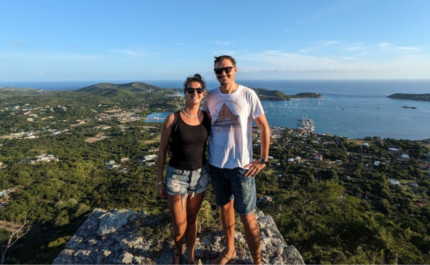 James and Danielle standing together with the ocean and boats in the background